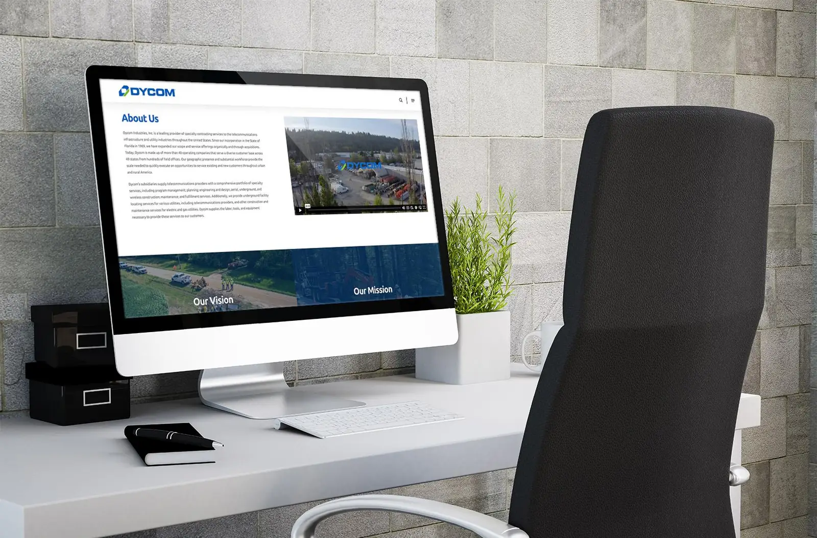 Redesigned Dycom About Us page on a desktop monitor, with company copy, a video, and Our Vision and Our Mission panels